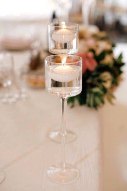 Güzel cam tezgahlarda yanan mumlar şeklinde dekorasyon. Çiçekler ve yüzen mumlarla süslenmiş güzel bir festival masası.