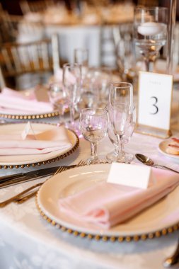 Lokantada tabakları ve temiz bardakları olan güzel bir masa. Restoranda üç numaralı misafir masası. Bir kafe veya restoranda ayrılmış bir masanın dikey fotoğrafı