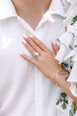 Yüzük ve mücevher şeklinde güzel manikür ve aksesuarları olan bir kadının eli. Kadın erkeğine eliyle dokunuyor. İncili güzel bir yüzük.