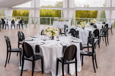 Açık bir verandada, kumaş tepe örtüsü olan bir restoranda çiçeklerle süslenmiş masalara servis yapardı. Misafir kabul etmek için hazırlıklar. Gelin ve damadın şerefine bir ziyafet.