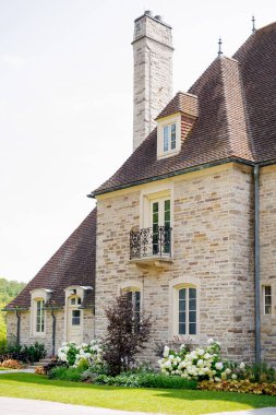 Döşeme çatılı eski güzel bir bina ve çiçeklerle süslenmiş bir kapısı olan bir giriş. Kesilmiş çimenleri ve güzel pencereleri olan iyi korunmuş eski bir bina.