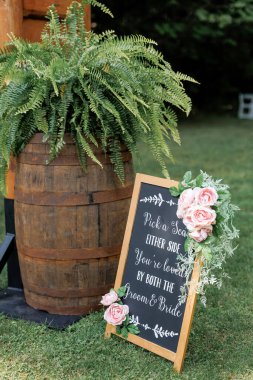Açık hava düğün töreni için düğün süslemeleri bir çimenlikte yakın plan. Gelin ve damat için dilekler bir tahtanın üzerinde ve eski bir fıçının üzerinde yemyeşil bir eğrelti otu düğün töreninde bir süs olarak.