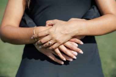 Bir adam dışarıda dikilirken karısına arkadan sarılıyor. Kadın, onu kucaklayan kocasına nazikçe elini sürdü. Aşk ve ortaklık kavramı. Çiftler ellerini kapatsın.