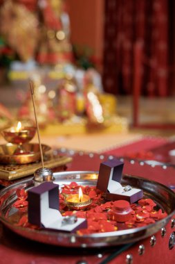 Ayrı mücevher kutularında iki alyans. Gelin ve damadın gümüş alyansları, yanan mumlar ve kırmızı gül yaprakları, aroma çubuğu. Geleneksel Hint düğününün detayları