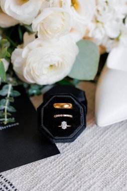 Gelin ve damadın nikah yüzüğü ve nişan yüzüğü. Mücevher kutusundaki bir çift için altın alyanslar. Gelinin aksesuarlarının arka planında yüzükler var.