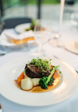 Lokantada servis edilen et yemeği mesela. Şölende sebzeli kırmızı et ve şifalı otlar. Patates yastığının üzerinde zarif bir şekilde servis edilen et yemeği ve düğünde üzerinde filizlenen otlar.