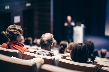 Sözcü, iş konferansında konferans salonunda konuşma yapacak. Konferans salonundaki tanınmayan insanların arka görüntüsü. İş ve girişimcilik kavramı