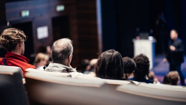 Sözcü, iş konferansında konferans salonunda konuşma yapacak. Konferans salonundaki tanınmayan insanların arka görüntüsü. İş ve girişimcilik kavramı