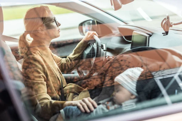 母親に集中運転に家族の車を実行している間にエランド彼女の赤ん坊睡眠で幼児車の座席によって彼女のサイト — ストック写真