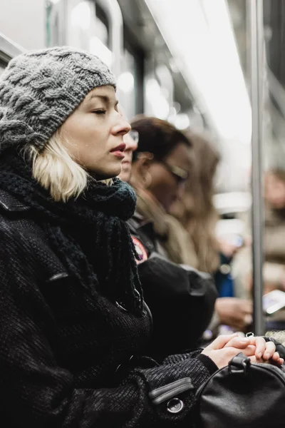 美しい金髪白人女性の冬のコートを着ているラッシュアワーで地下鉄で移動しながら昼寝します 公共交通機関 — ストック写真