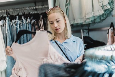 Kadın elbisesi alışveriş. Kadın müşteri iç giyim mağazasında moda giysiler bakarak.