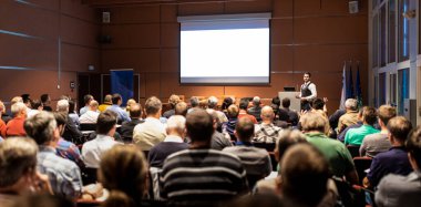 İş toplantısında konferans salonunda konuşma yapan konuşmacı. Konferans salonundaki tanınmayan insanların arka görüntüsü. İş ve girişimcilik kavramı.