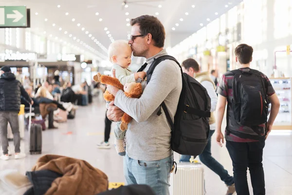 父は子供と一緒に旅行し 飛行機に乗るのを待っている空港ターミナルで幼児の男の子と抱き合ってキスをします 子供と一緒に旅行するコンセプト — ストック写真
