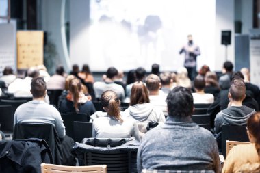 Sözcü, iş konferansında konferans salonunda konuşma yapacak. Konferans salonundaki tanınmayan insanların arka görüntüsü. İş ve girişimcilik kavramı.