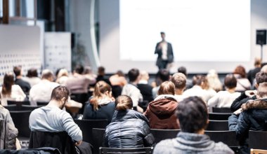 Sözcü, iş konferansında konferans salonunda konuşma yapacak. Konferans salonundaki tanınmayan insanların arka görüntüsü. İş ve girişimcilik kavramı.