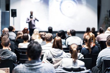 Sözcü, iş konferansında konferans salonunda konuşma yapacak. Konferans salonundaki tanınmayan insanların arka görüntüsü. İş ve girişimcilik kavramı.
