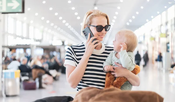 Matka Rozmawia Przez Telefon Komórkowy Podczas Podróży Dzieckiem Trzymając Swojego — Zdjęcie stockowe