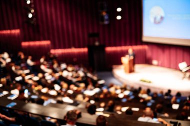 İş ve girişimcilik sempozyumu. İş toplantısında kadın konuşmacı bir konuşma yapıyor. Konferans salonunda dinleyiciler. İzleyicilerin tanınmayan katılımcılarının arka görünümü.