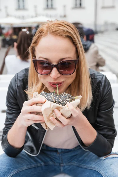 Αρκετά Νεαρή Ξανθιά Αστείο Γυναίκα Τρώει Χάμπουργκερ Υπαίθρια Στην Οδό — Φωτογραφία Αρχείου