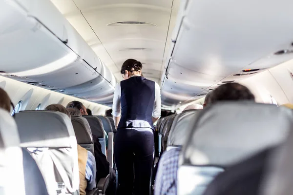 Uçakta Koltuklarda Yolcular Koridorda Yürüyen Insanlara Hizmet Eden Üniformalı Hostesler — Stok fotoğraf
