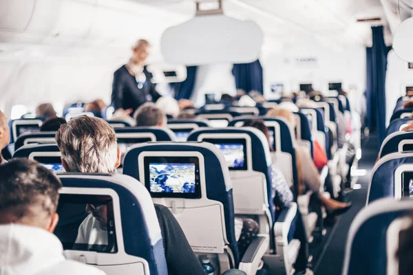 Uçakta Koltuklarda Yolcular Koridorda Yürüyen Insanlara Hizmet Eden Üniformalı Hostesler — Stok fotoğraf