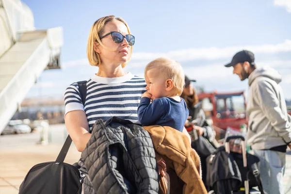 母亲和他年幼的男婴一起旅行 在候机楼前排队等候公共汽车时 妈妈提着旅行包和她的男婴 — 图库照片