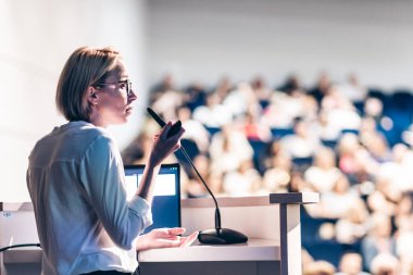 Kadın konuşmacı şirket iş konferansı hakkında bir konuşma yapıyor. Konferans salonundaki tanınmayan insanlar. İş ve Girişimcilik etkinliği