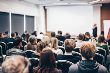 Sözcü, iş konferansında konferans salonunda konuşma yapacak. Konferans salonundaki tanınmayan insanların arka görüntüsü. İş ve girişimcilik kavramı