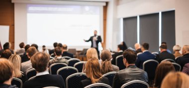 Sözcü, iş konferansında konferans salonunda konuşma yapacak. Konferans salonundaki tanınmayan insanların arka görüntüsü. İş ve girişimcilik kavramı