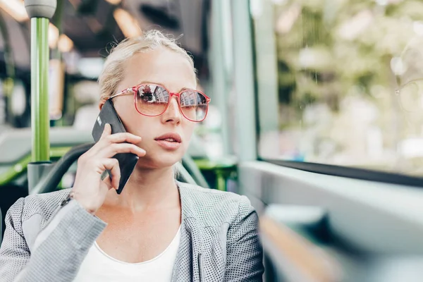 Otobüsle seyahat sarışın beyaz iş kadını cep telefonuyla konuşuyor. Toplu taşıma araçları ve çalışmaya commuting.