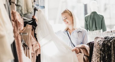 Kadın elbisesi alışveriş. Kadın müşteri iç giyim mağazasında moda giysiler bakarak.