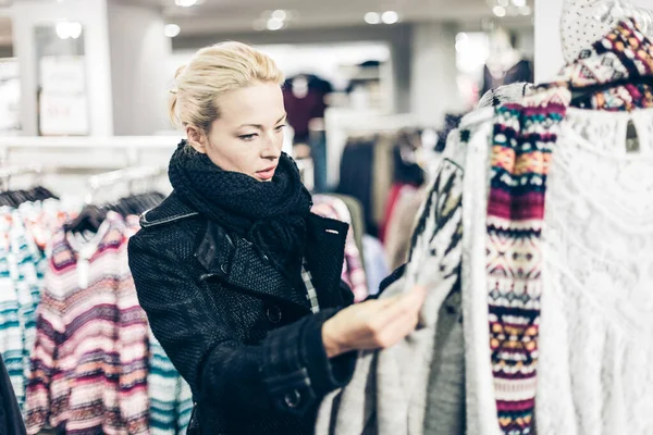 Frau Beim Kleiderkauf Shopper Die Kleidungsstücke Laden Betrachten Schöne Blonde lizenzfreie Stockbilder