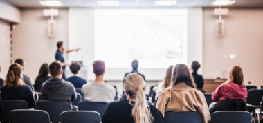 Sözcü, iş konferansında konferans salonunda konuşma yapacak. Konferans salonundaki tanınmayan insanların arka görüntüsü. İş ve girişimcilik kavramı