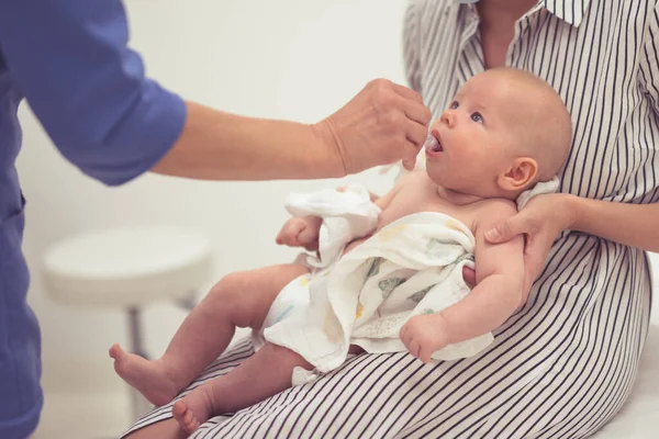 stock image Pediatrician administring oral vaccination against rotavirus infection to little baby in presence of his mother. Children health care and disease prevention.