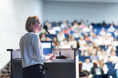 Kadın konuşmacı şirket iş konferansı hakkında bir konuşma yapıyor. Konferans salonundaki tanınmayan insanlar. İş ve Girişimcilik etkinliği