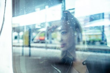 Kadın gezgin, tren penceresinden dışarıyı seyrediyor. İşe gidip gelen genç bayan otobüste ya da trende oturuyor.