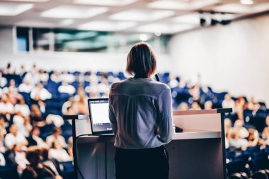 Kadın konuşmacı şirket iş konferansı hakkında bir konuşma yapıyor. Konferans salonundaki tanınmayan insanlar. İş ve Girişimcilik etkinliği