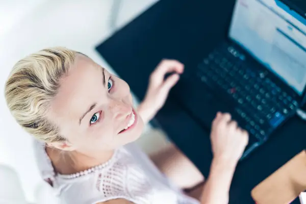 stock image Cheerful relaxed business woman, casualy dressed, typing ona a leptop computer, working from her home.