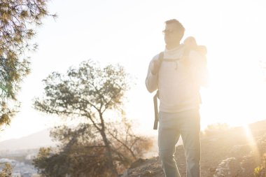 Gün batımında Malaga, İspanya 'da iz sürerken küçük oğlunu sırt çantasında taşıyan genç bir baba. Aile seyahati ve tatil konsepti.