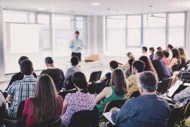 İş ve girişimcilik sempozyumu. Sözcü iş toplantısında bir konuşma yapacak. Konferans salonunda dinleyiciler. İzleyicilerin tanınmayan katılımcılarının arka görünümü.