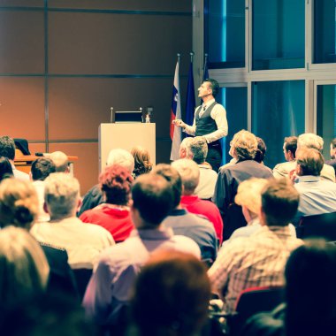 İş toplantısında konferans salonunda konuşma yapan konuşmacı. Konferans salonundaki tanınmayan insanların arka görüntüsü. İş ve girişimcilik kavramı.