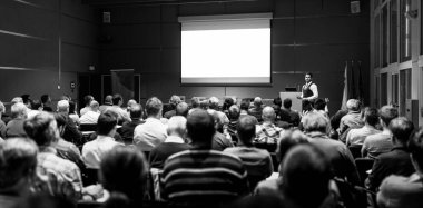 İş toplantısında konferans salonunda konuşma yapan konuşmacı. Konferans salonundaki tanınmayan insanların arka görüntüsü. İş ve girişimcilik kavramı.