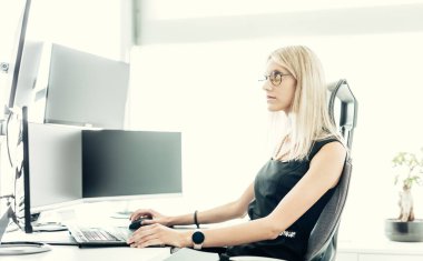 Kadın finansal varlıklar yöneticisi, çevrimiçi ticaret, birden fazla bilgisayar ekranında çizelgeleri ve veri analizlerini izlemek. Modern iş kadını konsepti.