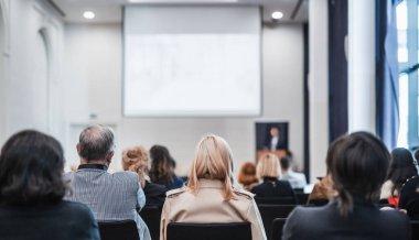 Speaker giving a talk in conference hall at business event. Rear view of unrecognizable people in audience at the conference hall. Business and entrepreneurship concept clipart