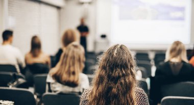 Sözcü, iş konferansında konferans salonunda konuşma yapacak. Konferans salonundaki tanınmayan insanların arka görüntüsü. İş ve girişimcilik kavramı