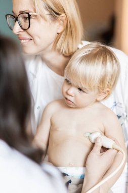 Küçük bir çocuk kalp üfürümü için kalp ultrasonu ile kardiyolog tarafından çocuk doktoruna düzenli olarak muayene ediliyor.