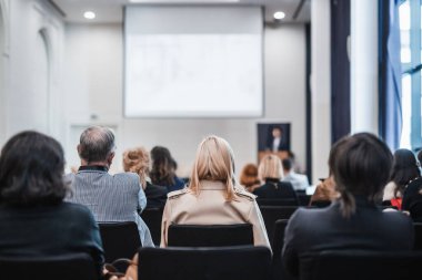 Sözcü, iş konferansında konferans salonunda konuşma yapacak. Konferans salonundaki tanınmayan insanların arka görüntüsü. İş ve girişimcilik kavramı