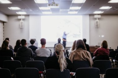 Sözcü, iş konferansında konferans salonunda konuşma yapacak. Konferans salonundaki tanınmayan insanların arka görüntüsü. İş ve girişimcilik kavramı