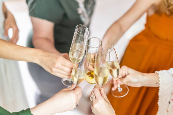 Birthday surprise party. Group of cheerful female friends celebrating personal success stories. Smiling girls toasting with glasses of champagne.