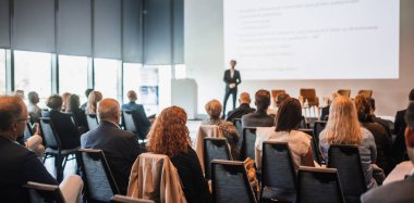 Sözcü, iş konferansında konferans salonunda konuşma yapacak. Konferans salonundaki tanınmayan insanların arka görüntüsü. İş ve girişimcilik kavramı
